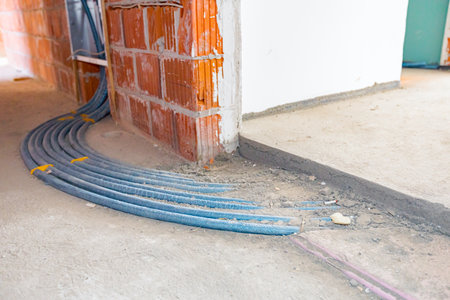 New distribution system mounted for central heating floor in a residential building under construction. Pile of blue pipelines passing through the concrete floor.の写真素材