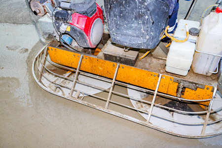 Close-up of self-leveling power trowel machine, for smoothing surface on concrete slab. Worker...