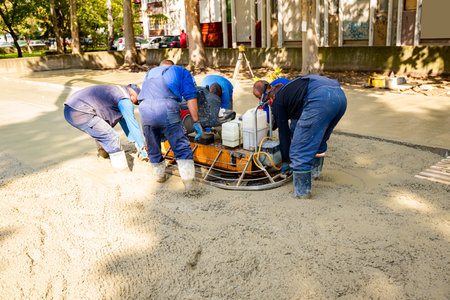 Few workers are moving, relocating power trowel with engine, machine for finishing, leveling concrete surface.の写真素材