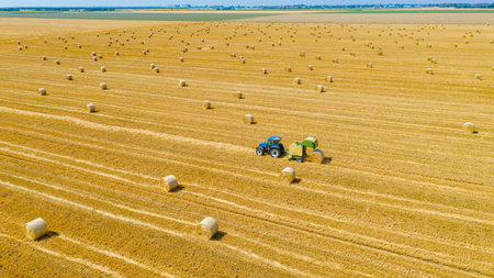 Above view on tractor as pulling round baler, machine that rolls up the straw and spits out a packed...
