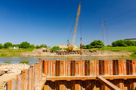 Installed rusty metal piles along river bank built in for bridge foundation at the construction...