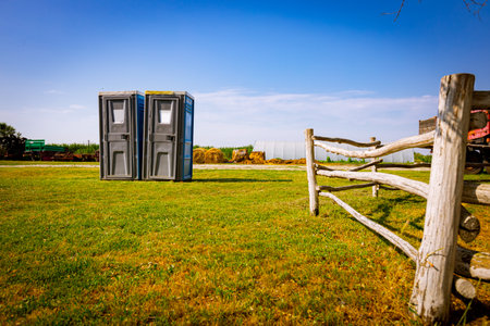 Two mobile plastic toilets, transportable public street placed at farmland, ranch with horse pen.の写真素材