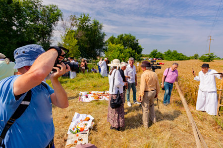 Elderly man photographer with blue hat is taking photo of people as dancing and having fun in performance of acoustic band.の写真素材