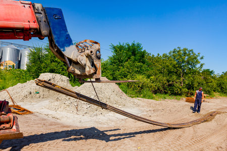 Forklift machinery for delivery and transport is lifting up selected bundle of long rusty armature...