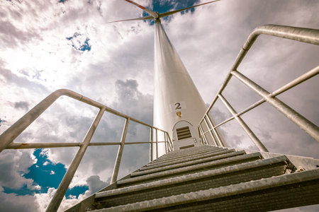 Low angle view of entrance, stairs with doorway into large wind power turbine for generating clean...
