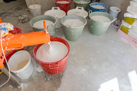 Electric mixer for mixes dry white putty, stir plaster and water in a several large buckets.の写真素材