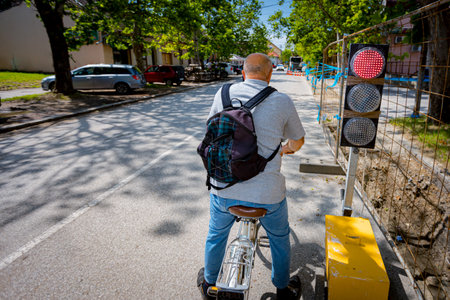 Cyclist is standing, waiting at red traffic light, semaphore.