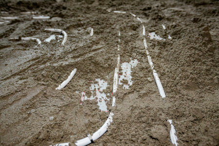 Semi-dry floor screed mixture of cement and sand poured over thin white tubes bended in complex...