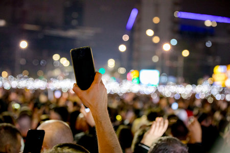 Belgrade, Serbia - March 15, 2025: Many people lift hand up hold mobile, cell phone with flashlight,...