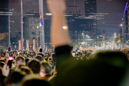 Belgrade, Serbia - March 15, 2025: Many people lift hand up hold mobile, cell phone with flashlight,...