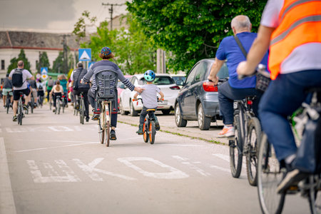 Children are cycling with a group of people in the city, riding bicycles. They are trying to draw attention to the danger for cyclists in traffic in an urban environment.の写真素材