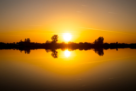 Scenic view of beautiful sunset in the evening time over lake, silhouette across water and...
