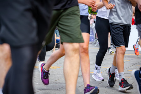 Large group of runners, athletes run in a street marathon competition, crowd of people running at urban race, low angle view on legs and feet of runners.の写真素材
