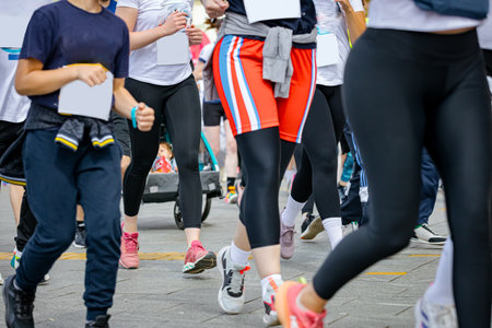Large group of runners, athletes run in a street marathon competition, crowd of people running at urban race, low angle view on legs and feet of runners.の写真素材