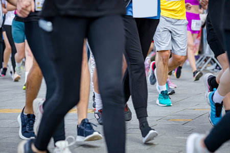 Large group of runners, athletes run in a street marathon competition, crowd of people running at urban race, low angle view on legs and feet of runners.の写真素材