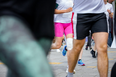 Large group of runners, athletes run in a street marathon competition, crowd of people running at urban race, low angle view on legs and feet of runners.の写真素材