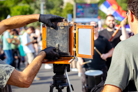 Photographer is taking photo of people, using old vintage retro camera, made of wood and metal,...