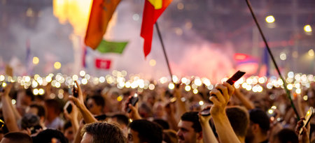 Blurred, unclear many people lift hand up hold mobile, cell phone with flashlight, light honoring...
