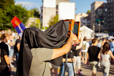 Photographer is taking photo of people, using old vintage retro camera, made of wood and metal,...
