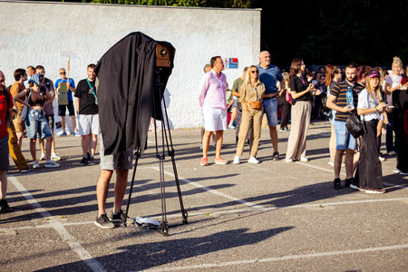Photographer is taking photo of people, using old vintage retro camera, made of wood and metal,...