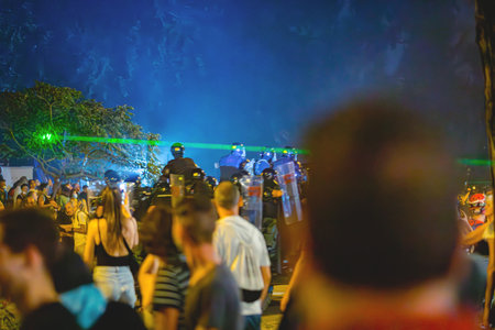 Group riot police with protective gear and shields surrounded with tear gas as response to citizen's...