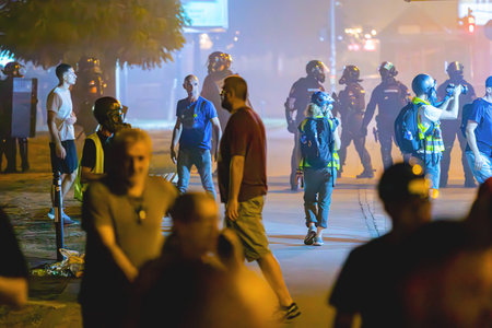Group riot police with protective gear and shields surrounded with tear gas as response to citizen's...