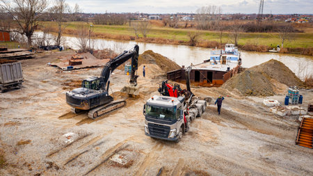Above view excavator and tow truck together they are pull out part of old freight vessel's bed,...
