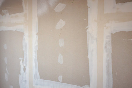 Front view of brown gypsum boards installed on the partition wall of building under construction at the construction site.の写真素材