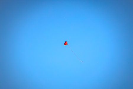Red heart shaped helium balloon fly high into the blue sky during a sunny day. Valentines Day. Love is in the air.の写真素材