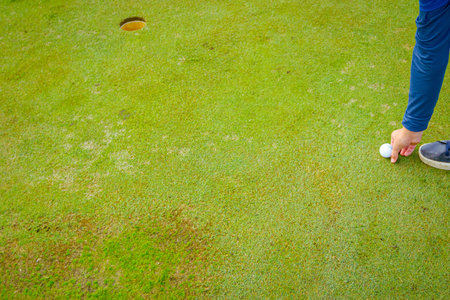 People are playing golf, grass field during golfing game, course. Focused golfer is picturesque golf course, aiming to putt near, hitting ball into hole, concentration and precision.の写真素材