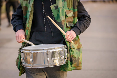 Musical performer is playing drums with sticks at protest against government corruption, regime, demand justice for 16 lives lost in tragic accident roof collapse, railway stationの写真素材