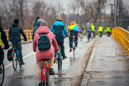 Group of young people cycling on rainy day, ride bicycles in city, driving in crowd they try to draw attention to the danger for cyclists in traffic, urban environment.の写真素材