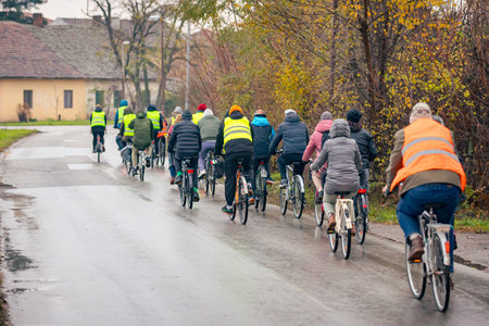 Group of young people cycling on rainy day, ride bicycles in city, driving in crowd they try to draw attention to the danger for cyclists in traffic, urban environment.の写真素材