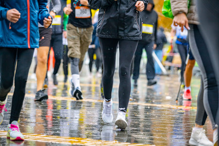 Low view on legs and feet, large group of runners, athletes are running street marathon competition, crowd of people   race at rainy day.の写真素材