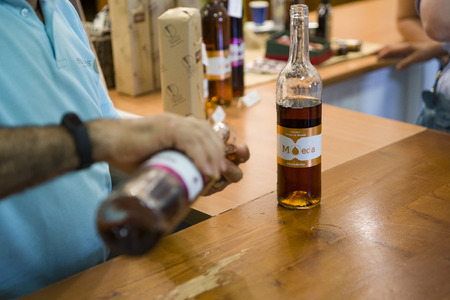Portugal, August 19, 2018: Madeira wine Tasting. In the foreground is a counter with a bottle of Madeira. In the background-a man pours wine. Selective focus.のeditorial素材