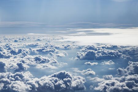 Sky with clouds. Under the clouds, the mountainous landscape and the ocean shore are faintly...