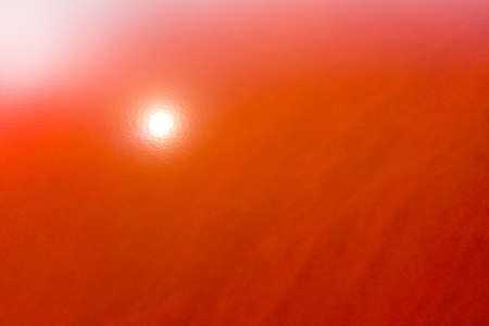 Orange surface of a salt lake with the reflection of the sun on the water. Shooting from a drone. Texture.の写真素材