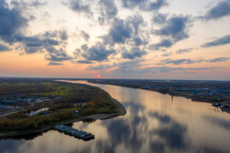 An industrial city located on the banks of a winding river at sunset. Shooting from a drone.の写真素材