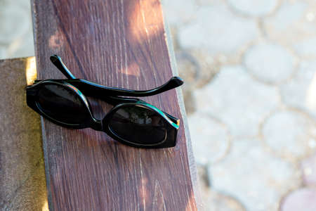 Forgotten sunglasses lie on a wooden bench. Selective focus. Copy space.の写真素材