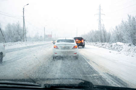 Russia, Nefteyugansk, December 23, 2019: view through the windshield of a car on a moving vehicle on a snow-covered road. Selective focus.のeditorial素材