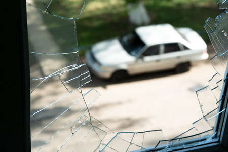 View of a car standing on the street, through a broken window in an apartment building. Selective focus. Defocused.の写真素材