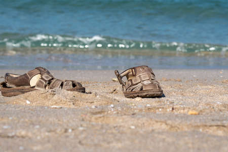 Men's sandals lie on the sand at the edge of the sea. Selective focus.の写真素材