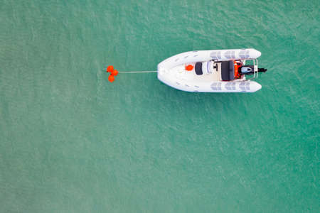 A white motor boat is placed on a red buoy in the middle of the sea. The view from the top. Copy...