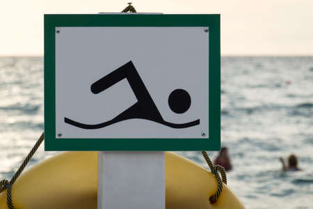 Beach sign in a green frame with the image of a floating person on the background of the sea. Selective focus.の写真素材