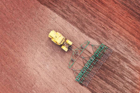Pre-sowing soil preparation. Tractor harrows the field. Shooting from the air. Copy space.の写真素材