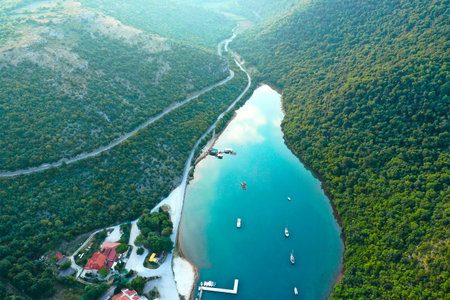 Fragment of the gulf of lima in the mountains of croatia. there is an oyster farm and a restaurant on the bay. Ships are sailing along the canal. Shooting from a drone.の写真素材