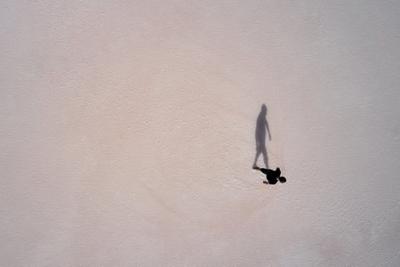 A lone figure of a man walking on the surface of a pink-colored salt lake. Shooting from a drone. Copy space.の写真素材