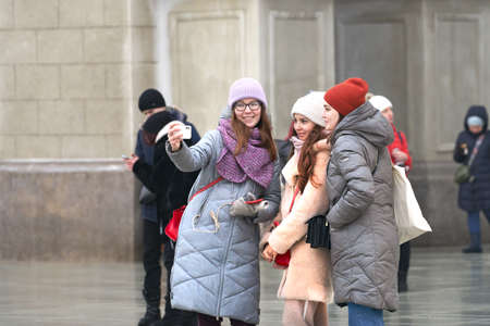 Russia, Moscow, January 24, 2021: three friends are photographed on a smartphone on the street.のeditorial素材