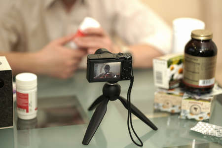 An adult male leads a video blog about alternative medicine. In his hands, he holds a jar of herbal...