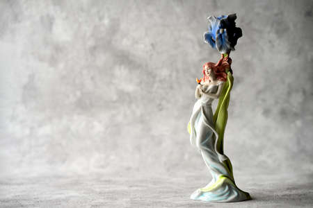 Russia, Naberezhnye Chelny, February 11, 2021: Porcelain candle holder in the shape of a young woman with a butterfly in her hand on a vintage gray background. Copy space.のeditorial素材